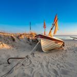 Holzpromenade mit Schild Ostseebad Koserow und Glockenturm am Strand