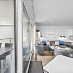 Wohnung mit Balkon, Küche und Wohnbereich. Blick auf Hafen mit Booten.