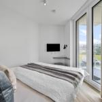 Schlafzimmer mit Bett, Fernseher und Balkonansicht.