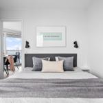 Schlafzimmer mit Bett, Kissen und Wandbild. Durchgang zur Küche und Terrasse.