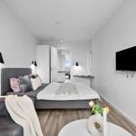 Schlafzimmer mit Bett, Wandlampe und Fernseher an der Wand