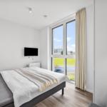 Schlafzimmer mit Bett, TV und großem Fenster mit Blick nach draußen.