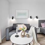 Ein Wohnbereich mit grauem Sofa, runden Tisch und Wandbild.