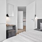 Schlafzimmer mit Bett, Kleiderschrank und Tisch. Durchgang zur Küche.