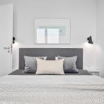 Schlafzimmer mit Bett, Wandbild und Nachttischen. Tür führt in die Küche.