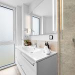 Badezimmer mit Dusche, Waschbecken und Fenster