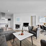 Wohnzimmer mit Sofa, Esstisch und Kamin. Küche und Schlafzimmer sind sichtbar.