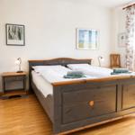 Schlafzimmer mit Holzbett, Nachttisch und Bildern an der Wand.