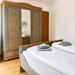 Schlafzimmer mit Doppelbett, Holzmöbel und Spiegeltüren im Schrank.