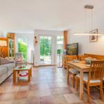 Wohn- und Essbereich mit Holztisch, Sofa und Glastüren zum Garten.