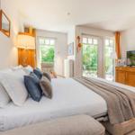 Schlafzimmer mit Bett, TV und Terrasse. Fenster und Tür führen nach draußen.