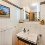 Badezimmer mit Waschbecken, Spiegel, Heizung und Wandbild.
