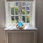 Ein Fenster mit Rollladen und einem Schale mit Muscheln auf dem Sims.
