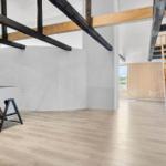 Großes Zimmer mit Holzboden, Treppe und Tischfußball. Holzbalken und Fenster sichtbar.