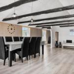 Essbereich mit Tisch und Stühlen, Wohnbereich mit Sofa und Holzbalken an der Decke.