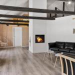 Wohnzimmer mit Kamin, Sofa und Holzbalken an der Decke.