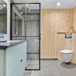Bad mit Dusche, Waschbecken und Toilette an Holzwand