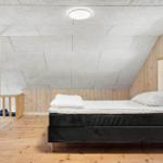Schlafzimmer mit Bett, Holzfußboden und Fenster. Decke aus Holz und Kacheln.