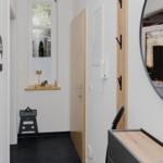 Eingangsbereich mit Wandspiegel, Tür und Fenster mit Holzbank.