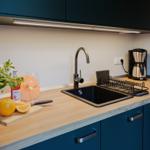 Küche mit Arbeitsfläche, Spüle, Kaffeemaschine und Pflanze.