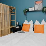 Schlafzimmer mit Bett, Kleiderschrank und Wandregal mit Pflanzen.