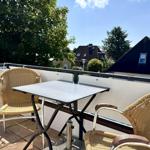 Terrace with table and two chairs. View of houses and trees.