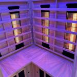 Sauna mit Holzwand und Heizungselementen, beleuchtet mit lila Licht.