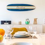 Esszimmer mit Tisch, Stühlen und Dekoration. Wanddekoration mit Surfboard-Design.