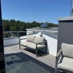 Terrasse mit Sitzgelegenheiten und Blick auf Wald und Gebäude