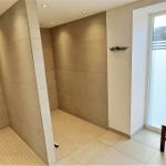 Shower with rainfall head and wooden bench by window