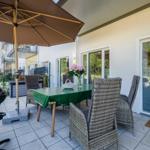 Terrace with table, chairs, umbrella, and grill. Entrance to the kitchen.