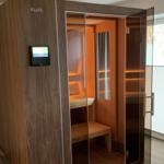 Sauna with glass door and digital control. Wooden interior with bench and lighting.