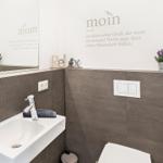 Bathroom with sink, mirror, and toilet. Wall decoration with text and plants.