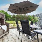 Terrace with umbrella, lounge chair, and dining table with flowers.