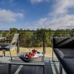 Terrasse mit Sitzgruppe und Obstteller, Blick auf Wald und Himmel.