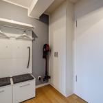 Eingangsbereich mit Garderobe, Sitzbank und Staubsauger. Holzboden und weiße Schränke.
