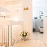 Helle Eingangshalle mit Treppe, Blumen und Blick in die Toilette.