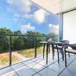 Terrasse mit Tisch und Stühlen, Blick auf Wald und Himmel.