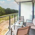 Terrasse mit Sitzgelegenheiten und Blick auf Wald und Strand.