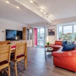 Wohn/Essbereich: Couch und Sessel, TV, Zugang zum Balkon