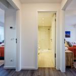 Durchgang mit Blick auf Bad und zwei Schlafzimmer mit Betten und Holzmöbeln.