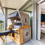 Terrasse mit Bootsbalkonmöbeln und Blick auf Wald. Schlafzimmer mit Bett und dunkler Wand.
