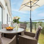 Terrasse mit Tisch, Stühlen und Sonnenschirm. Blumen und Obst auf dem Tisch.