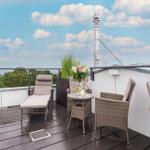 Dachterrasse mit Sitzgelegenheiten und Blick auf Himmel und Bäume.