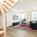 Wohnbereich/Essbereich: Sofa, TV, Beschattungs-Plissess, Treppenaufgang zur Dachterrasse, Zugang zum Balkon