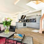 Wohnbereich/Essbereich: Sofa, TV, Beschattungs-Plissess, Treppenaufgang zur Dachterrasse, Zugang zum Balkon