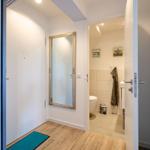 Hallway with mirror and door to bathroom. Bathroom with toilet and towel.