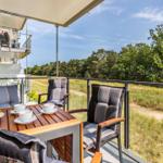 Terrace with table, chairs, and view of forest. Sunshade and fruit on table.