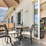 Terrace with table, chairs, and awning. Entrance into living area with kitchen.