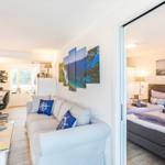 Wohn-/Essbereich: Sofa, Smart-TV, Essbereich, Treppenaufgang zur Dachterrasse, Zugang zum Balkon